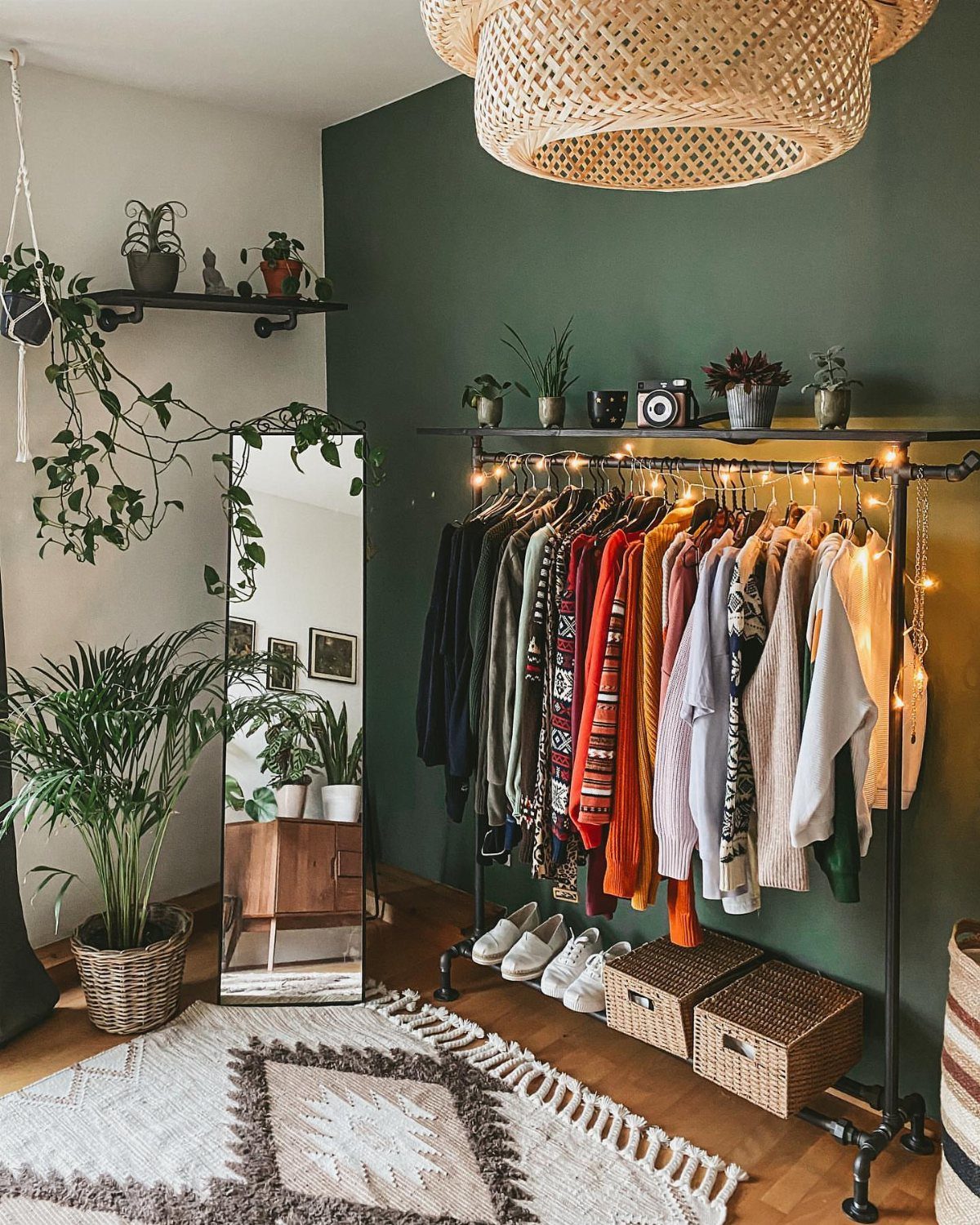 15 Apartment Decor Inspiration Ideas for Small Living Spaces 6 Clothing rack with colorful clothes against a green wall with plants and mirror.