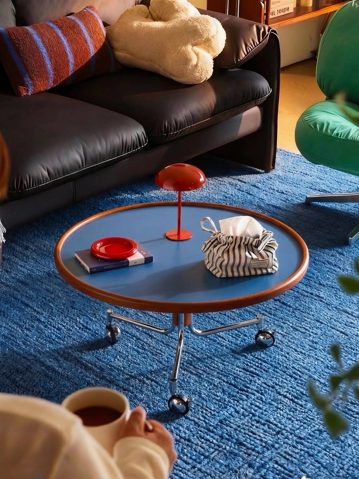 15 Apartment Decor Inspiration Ideas for Small Living Spaces 7 Round blue coffee table with wheels on a blue rug in a living room.