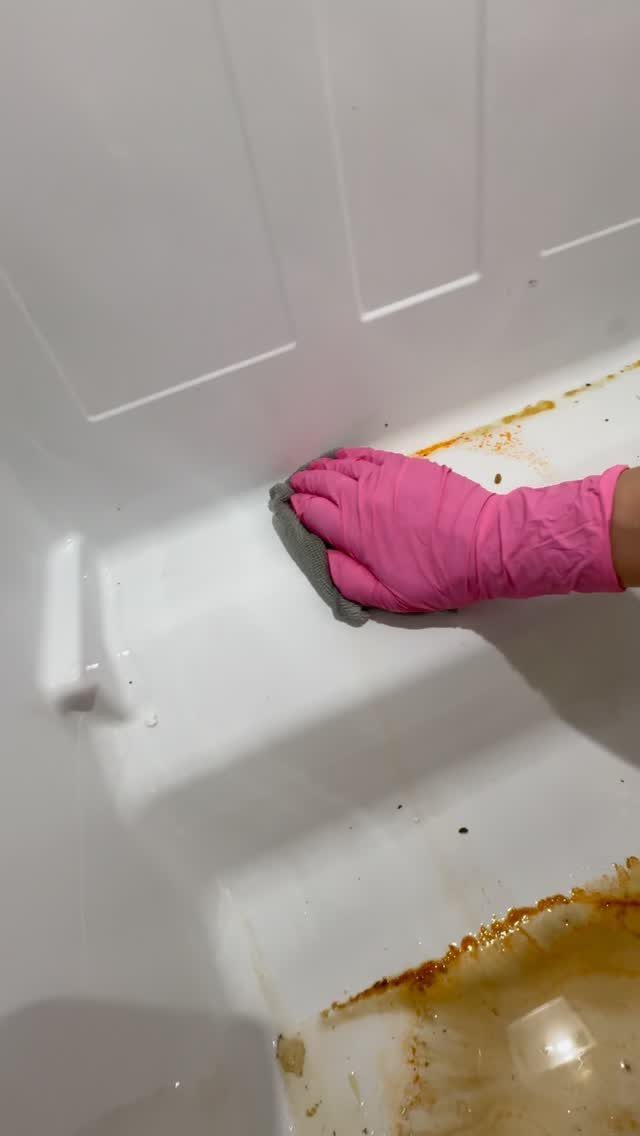 Apartment Deep Clean: 14 Areas to Scrub, Dust, and Vacuum 11 Hand in pink glove scrubbing a stained white bathtub with a grey sponge.