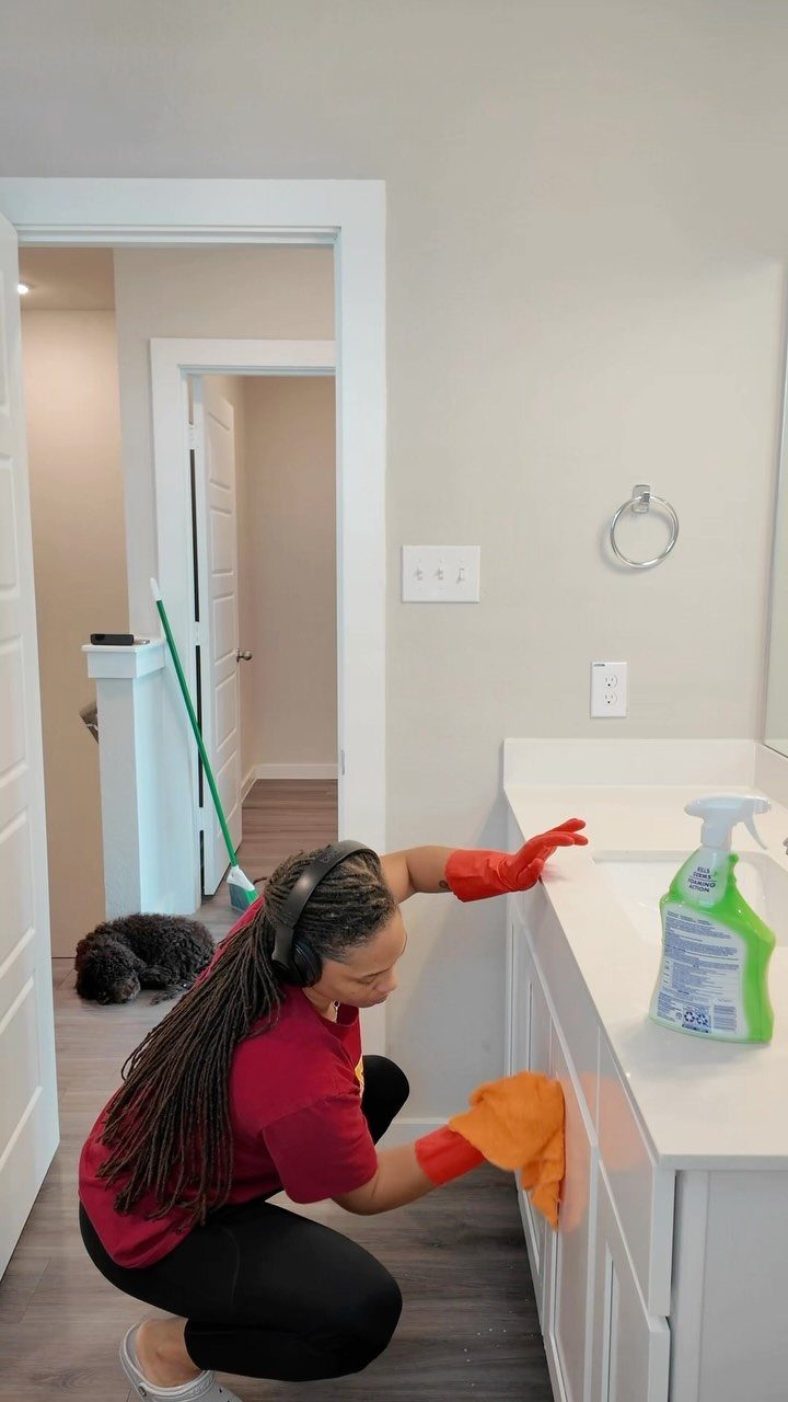 Apartment Deep Clean: 14 Areas to Scrub, Dust, and Vacuum 1 Woman in red gloves wiping white cabinet fronts with an orange cleaning cloth.