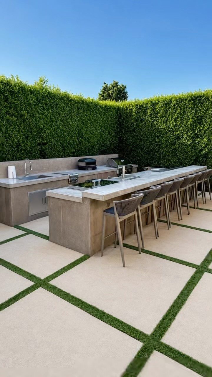 Modern grey concrete outdoor kitchen island with white countertop and grey bar stools.