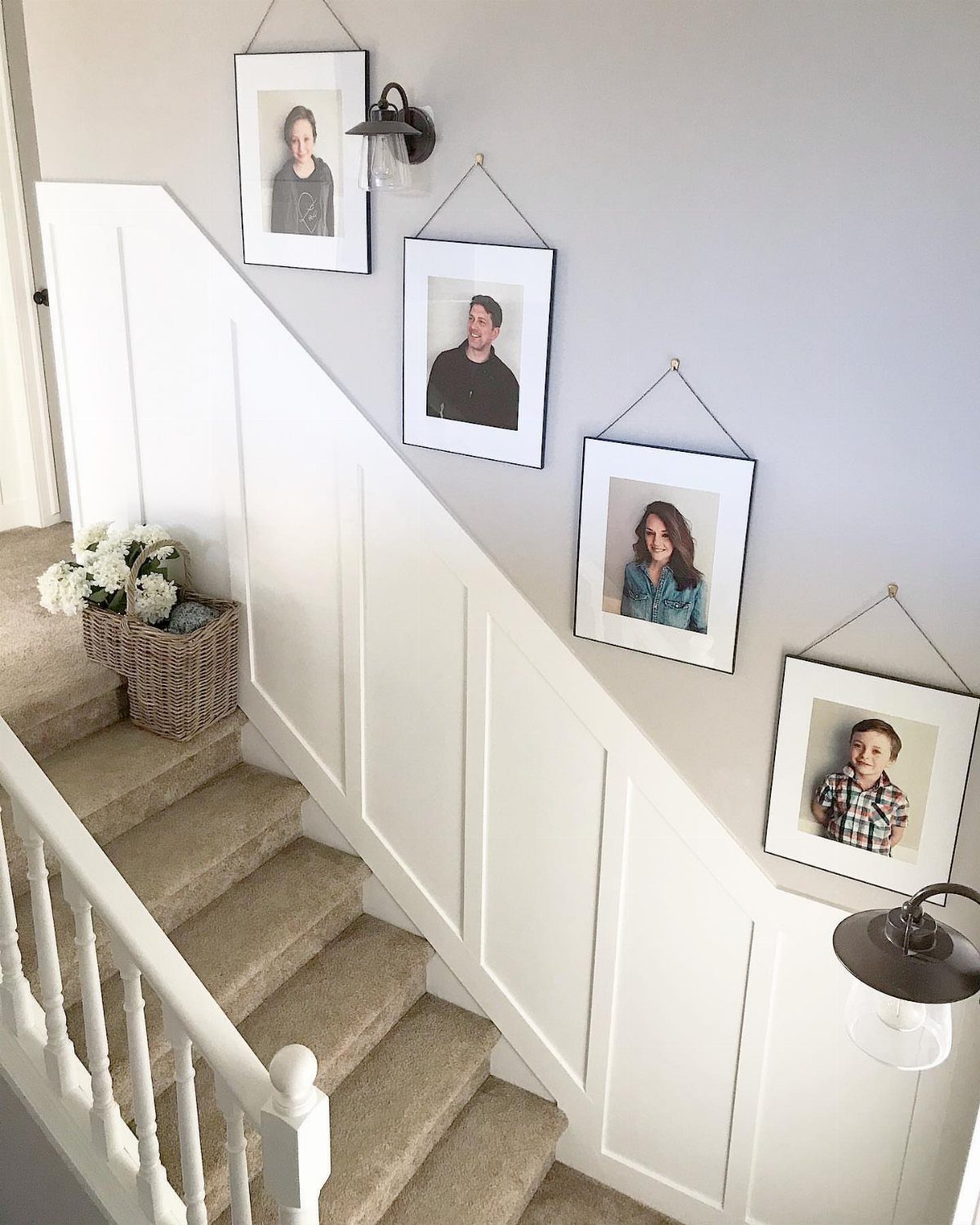 Board and Batten: 8 Styles That Update the Classic Wall Treatment 4 White board and batten wainscoting installed on a staircase wall with framed portraits hanging above.