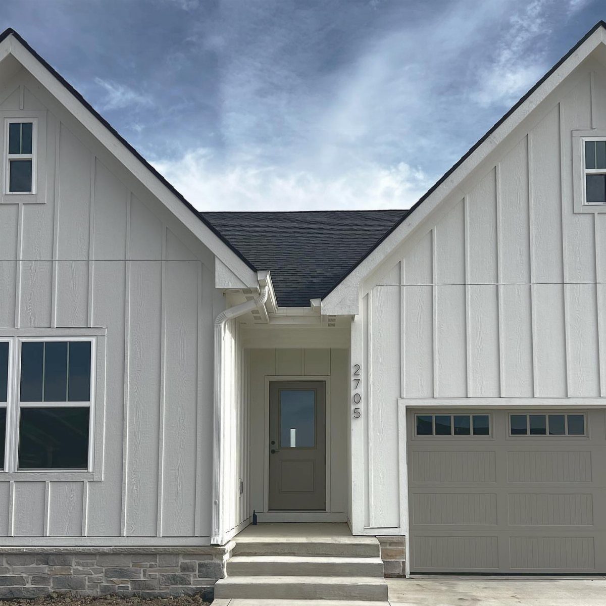 Board and Batten: 8 Styles That Update the Classic Wall Treatment 5 White modern farmhouse with vertical board and batten siding and a grey garage door.