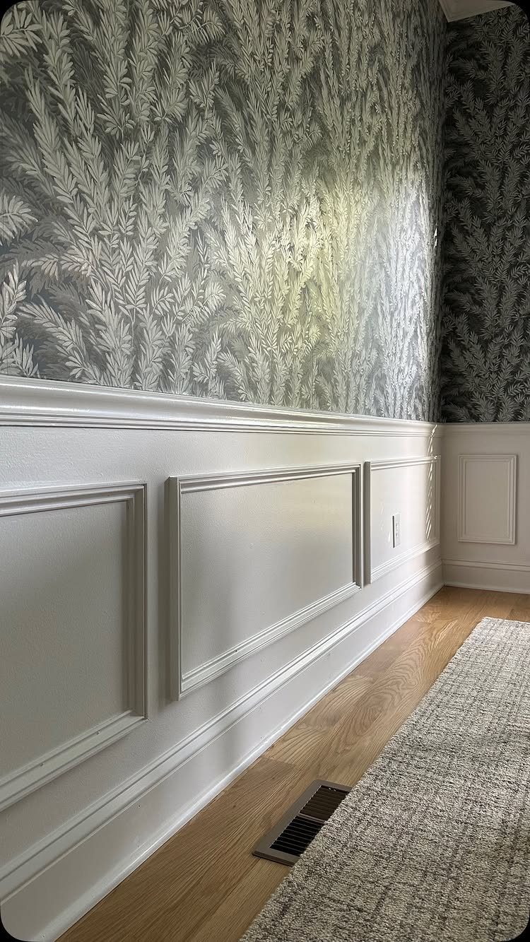 White rectangular box moulding panels installed on a wall below botanical patterned wallpaper.