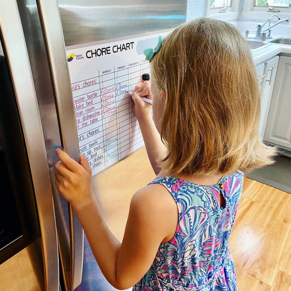 Chore List Ideas for the Family: 5 Charts and Lists to Use 4 Young girl checking off tasks on a chore chart attached to a refrigerator.