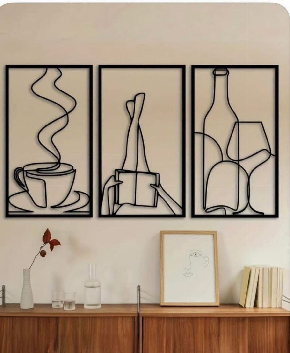 Three black metal line art panels depicting coffee, a book, and wine on a wall.