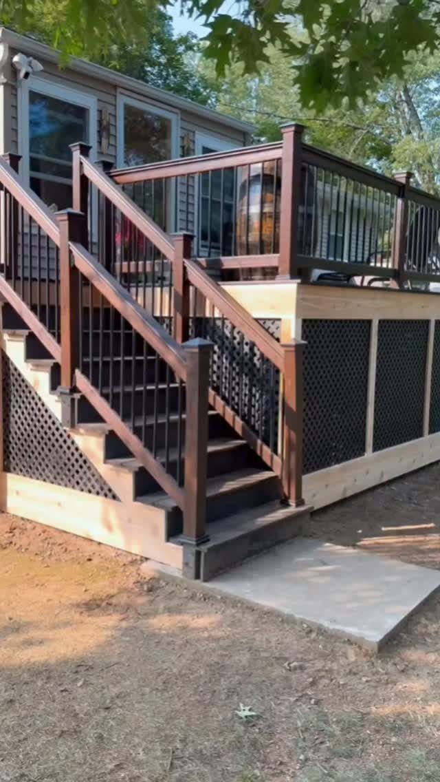 Raised wooden deck with black vinyl lattice underpinning and matching brown railings.
