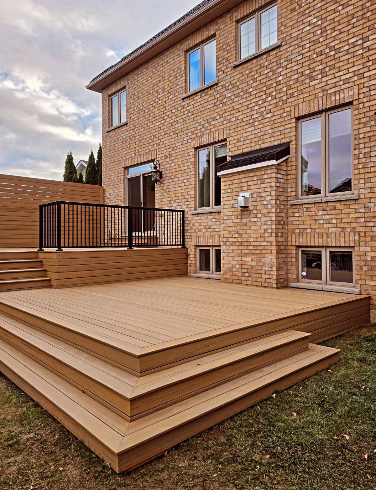 Brown composite deck with horizontal skirting boards attached to a brick house.