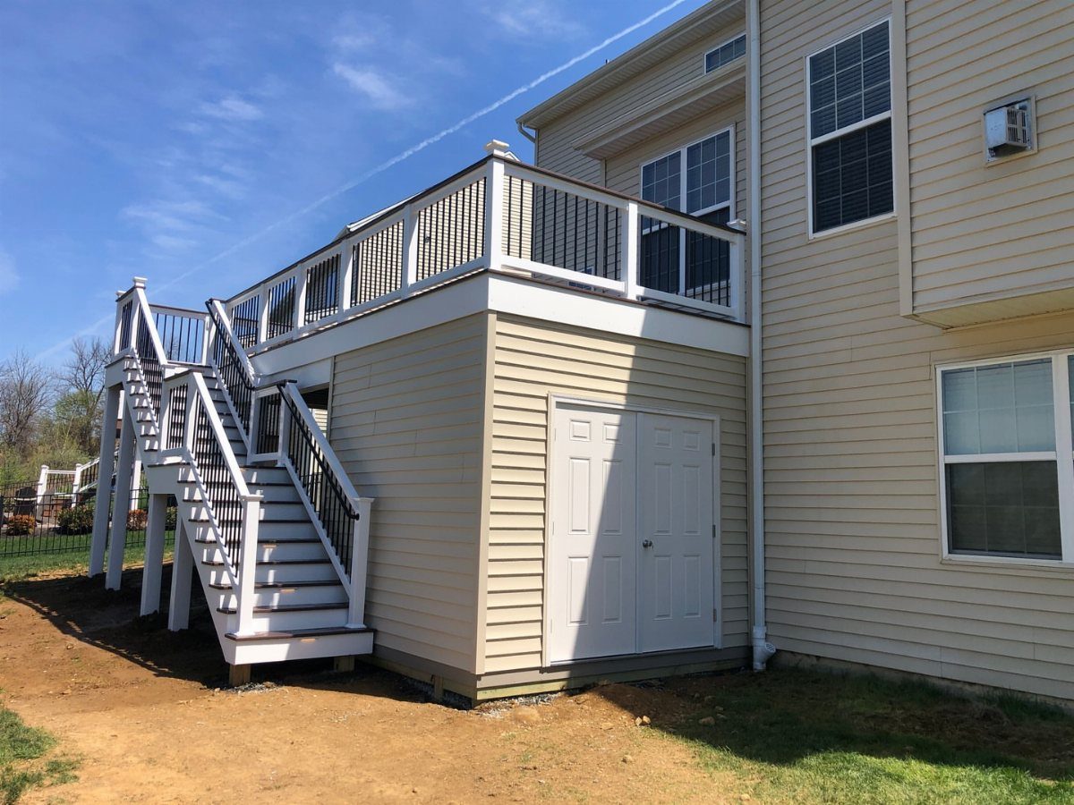 Raised deck with white railings and a siding-enclosed storage area underneath the platform.