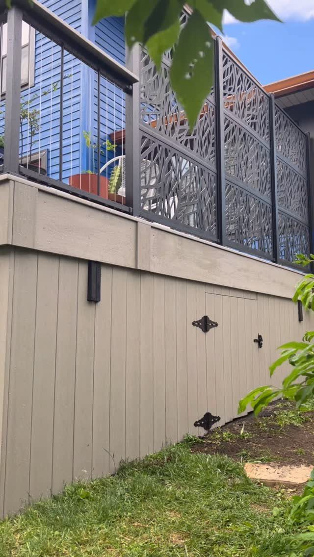 Raised wooden deck with grey skirting boards and decorative black metal railing screens.