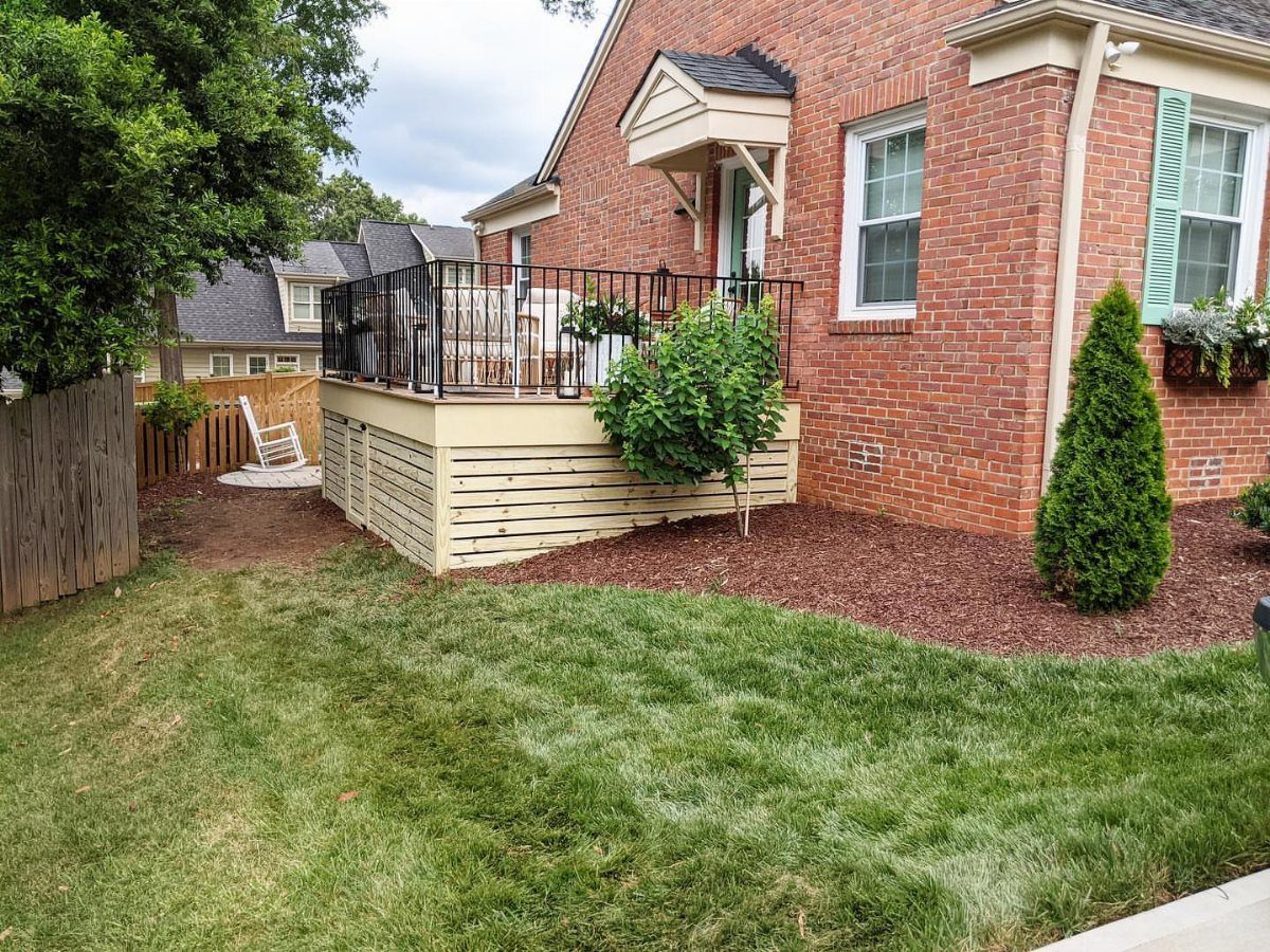 Raised deck with beige horizontal composite skirting boards against a red brick house.