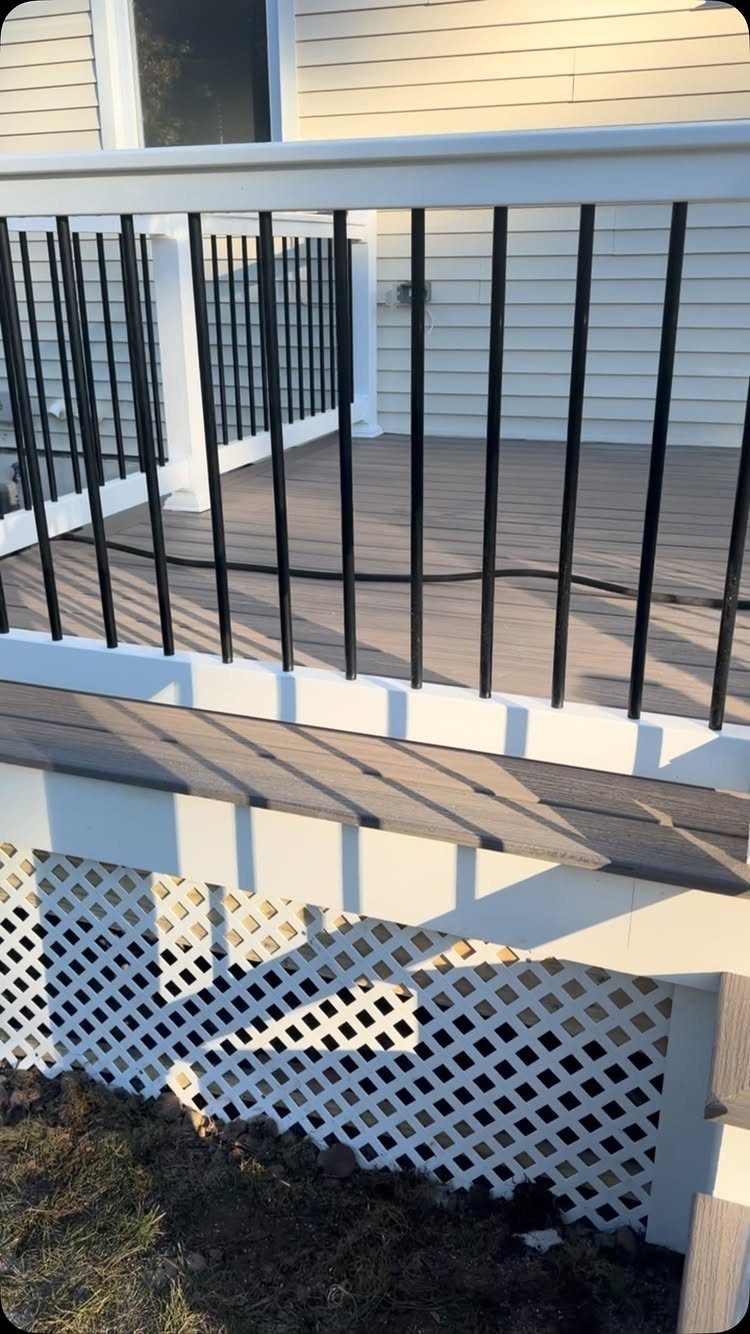 White vinyl lattice skirting installed under a raised wooden deck with white railings.