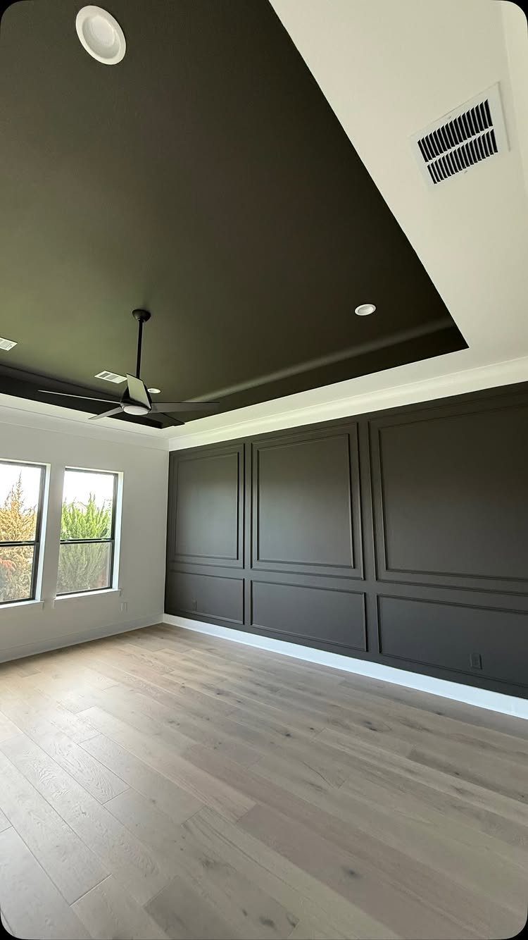 Modern living room with a black recessed false ceiling and dark grey paneled walls.