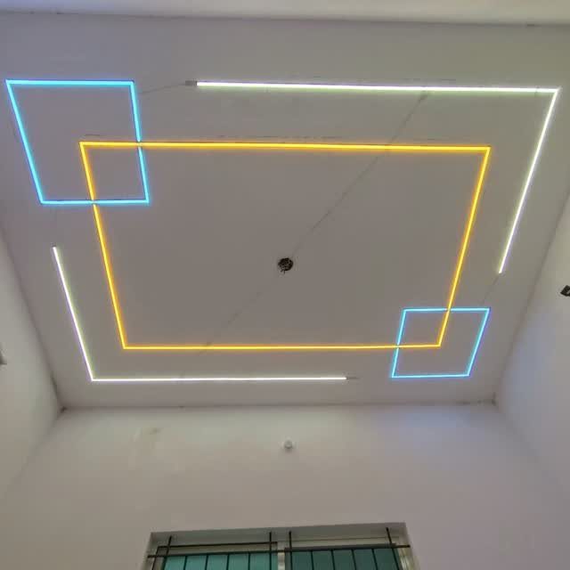 White false ceiling with overlapping blue and yellow neon rectangular light strips.