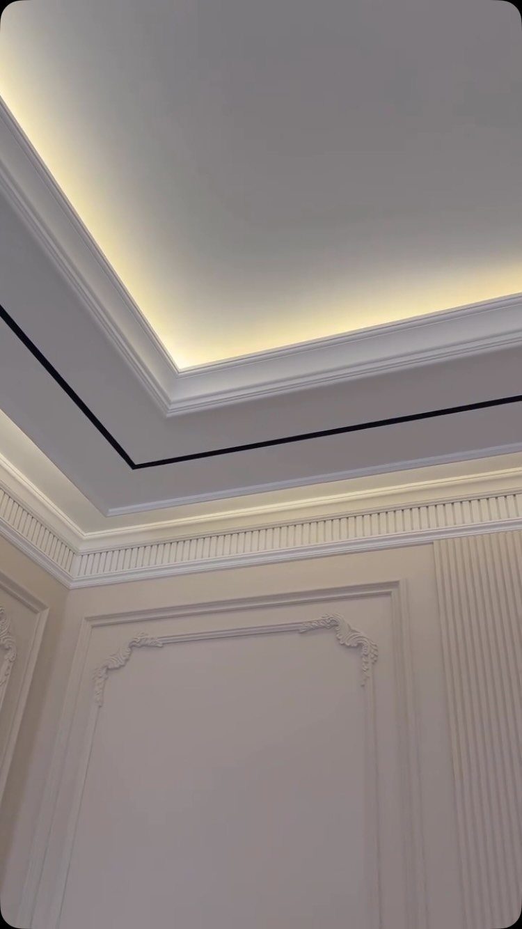 Layered white false ceiling with warm cove lighting and decorative wall molding.