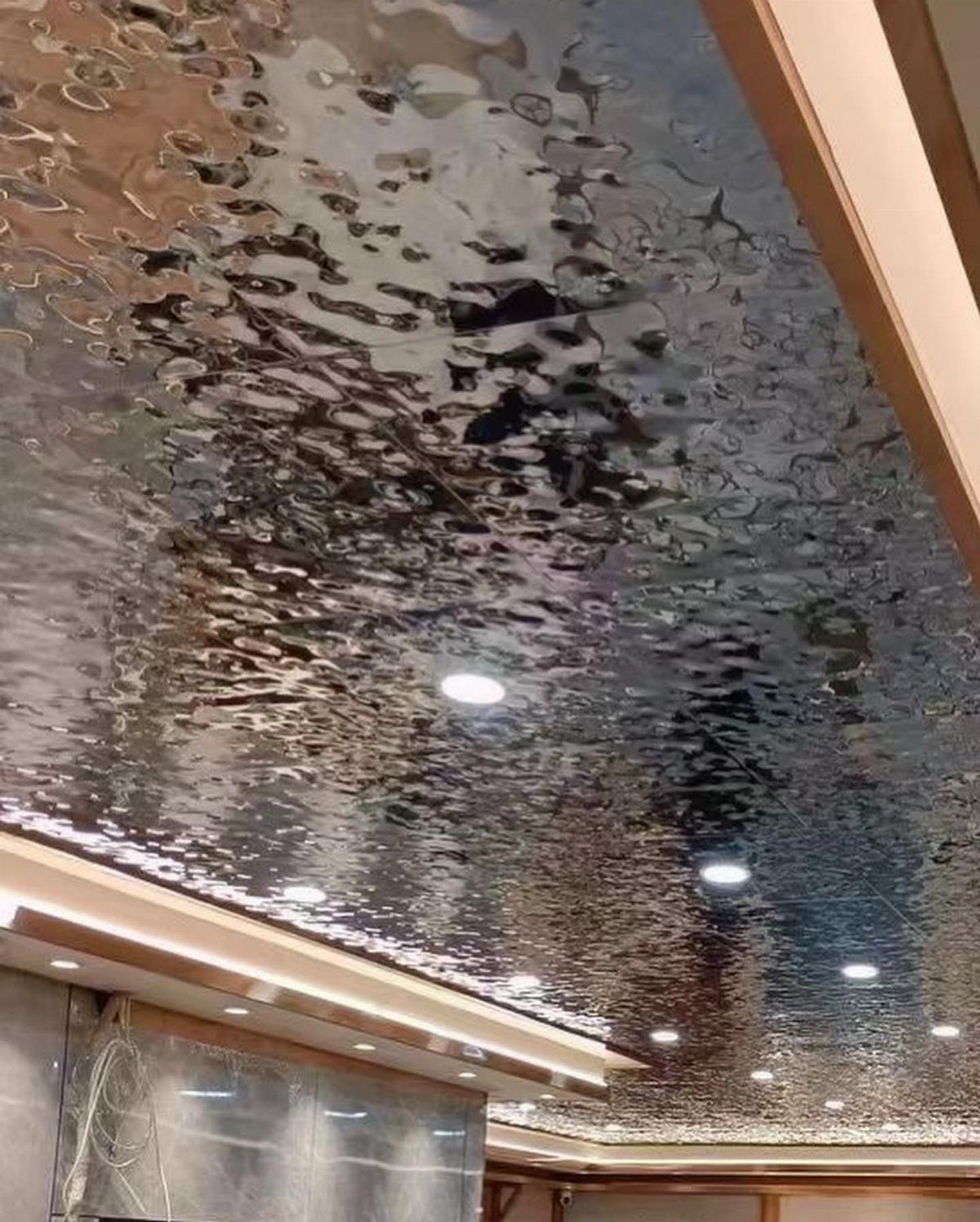Textured silver metal ceiling with rippled surface and recessed circular lighting.