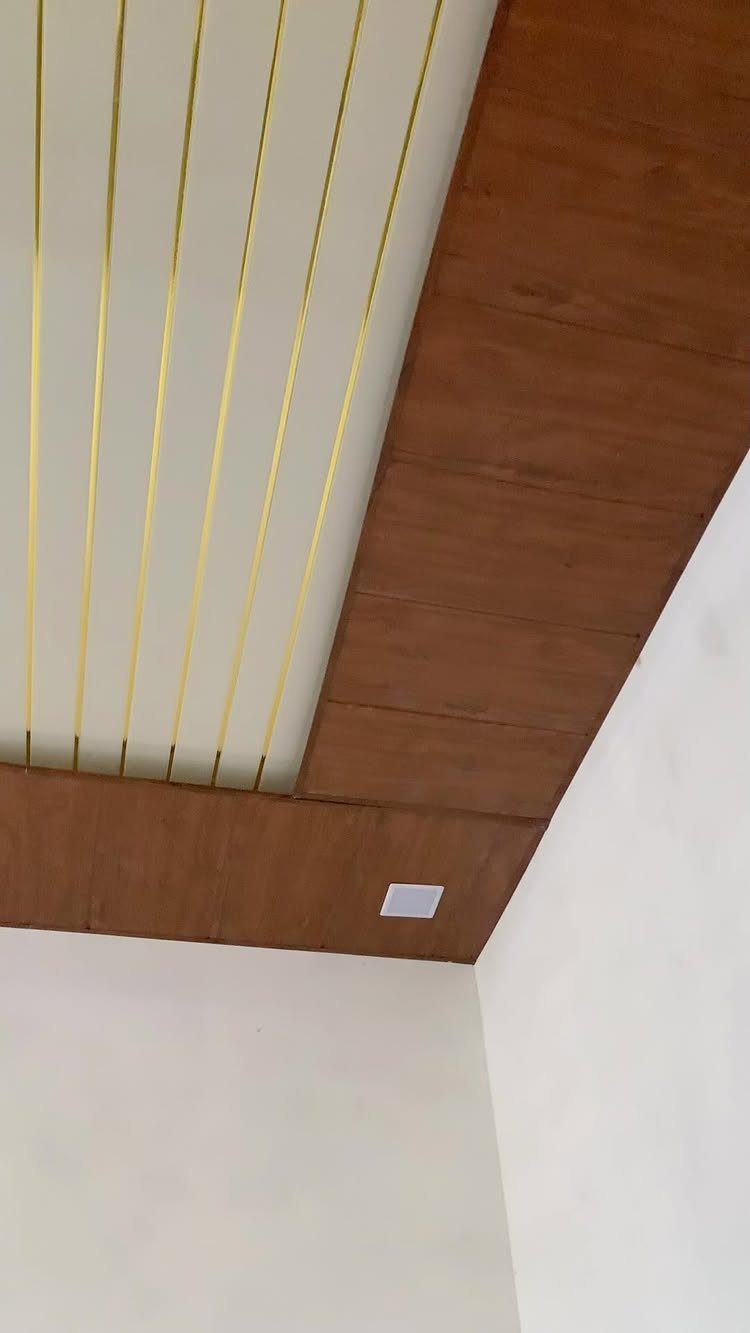 False ceiling with brown wood-grain PVC panels and a gold-striped white center.
