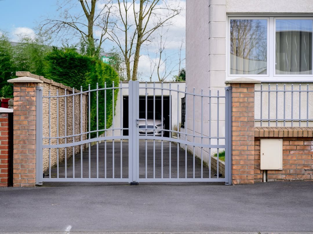 Fence Grill Design Modern: 28 Ideas from Steel to Aluminum 27 Grey metal fence and double gate with arched tops between brick pillars.