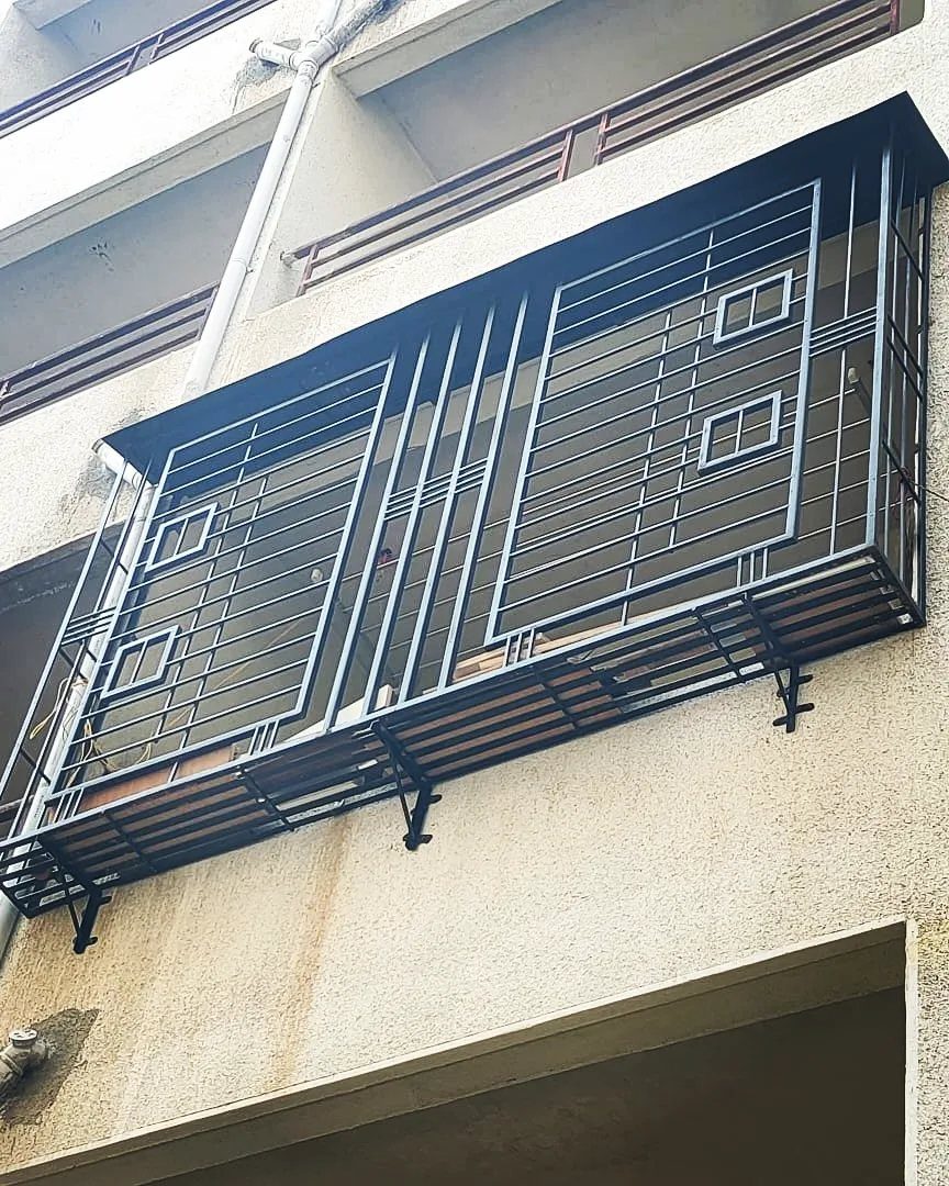 Fence Grill Design Modern: 28 Ideas from Steel to Aluminum 13 Black metal safety grille enclosing an outdoor balcony on a light-colored building.