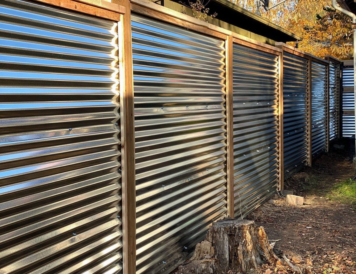 Fence Grill Design Modern: 28 Ideas from Steel to Aluminum 19 Corrugated silver metal fence panels with wooden posts in an outdoor setting.