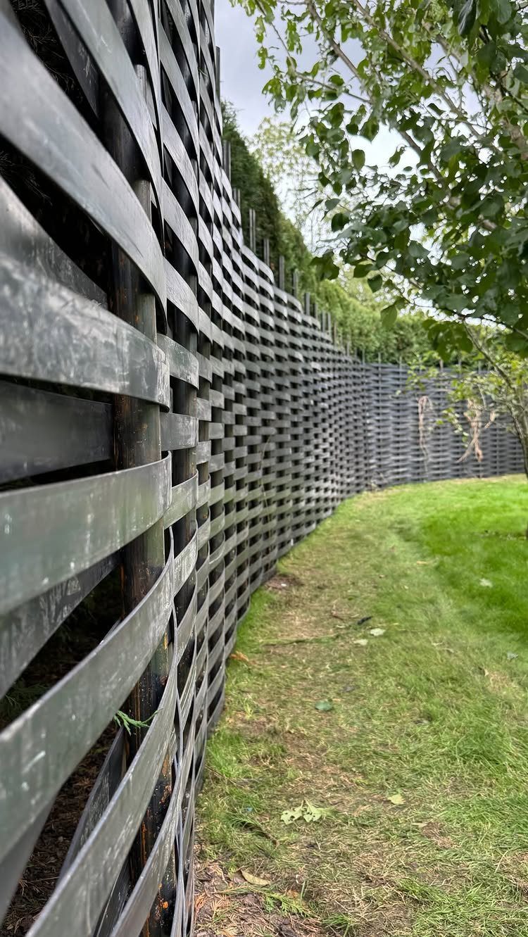 Fence Grill Design Modern: 28 Ideas from Steel to Aluminum 21 Curved modern black slat fence bordering a green lawn with lush trees.
