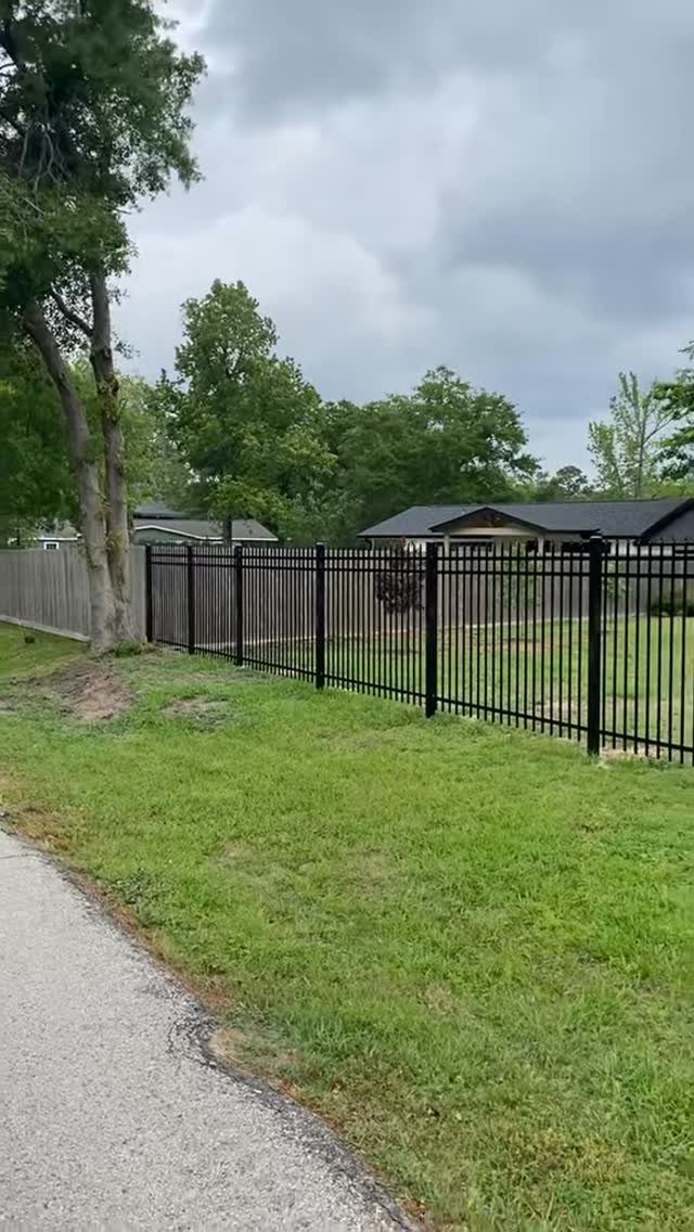 Fence Grill Design Modern: 28 Ideas from Steel to Aluminum 18 Black metal picket fence bordering a green lawn with trees and a house.