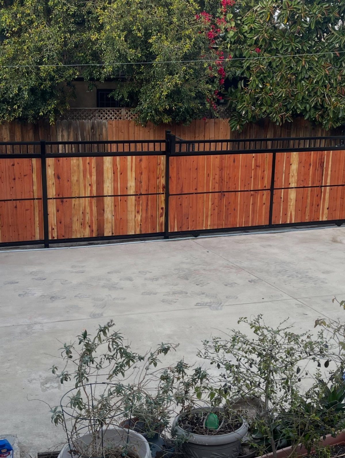 Fence Grill Design Modern: 28 Ideas from Steel to Aluminum 4 Wooden fence with horizontal planks and a black metal frame on a concrete patio.