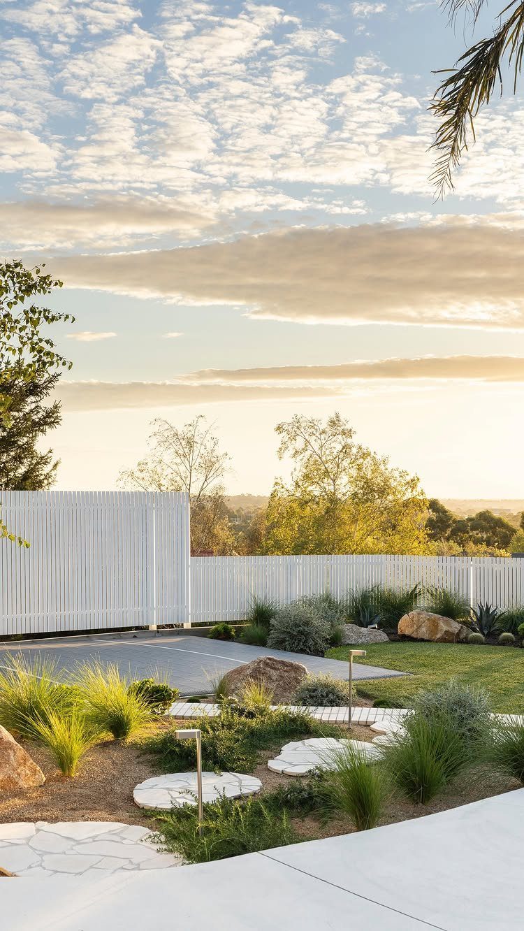 Fence Grill Design Modern: 28 Ideas from Steel to Aluminum 9 White vertical blade picket fence surrounding a modern landscaped backyard with stepping stones.