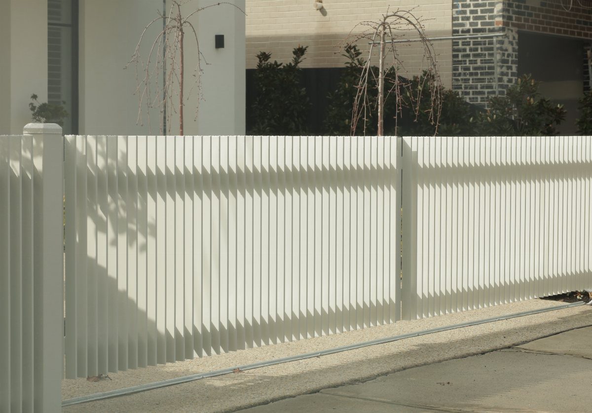 Fence Grill Design Modern: 28 Ideas from Steel to Aluminum 26 Modern white metal fence with vertical slats and geometric design along a sidewalk.