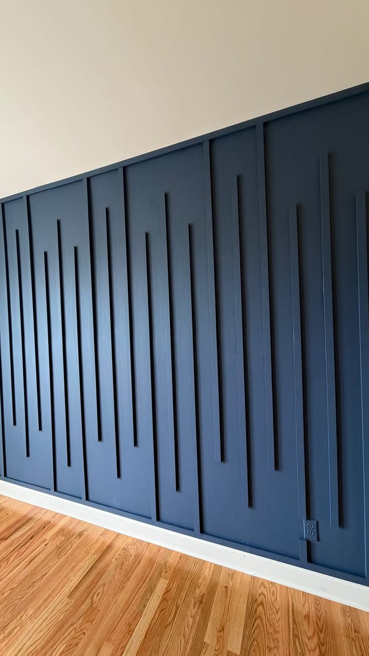 Dark blue accent wall with thin wooden slats arranged in an asymmetrical vertical pattern.