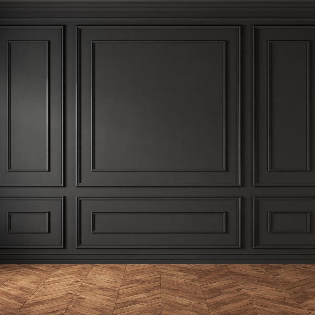 Dark grey wall with decorative rectangular molding panels above a herringbone wood floor.