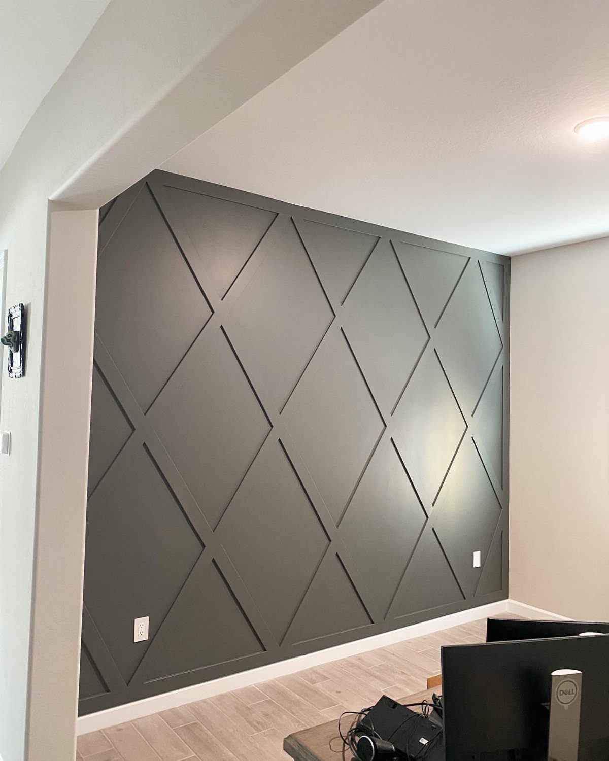 Dark grey wall with a geometric diamond pattern made of raised wooden molding.