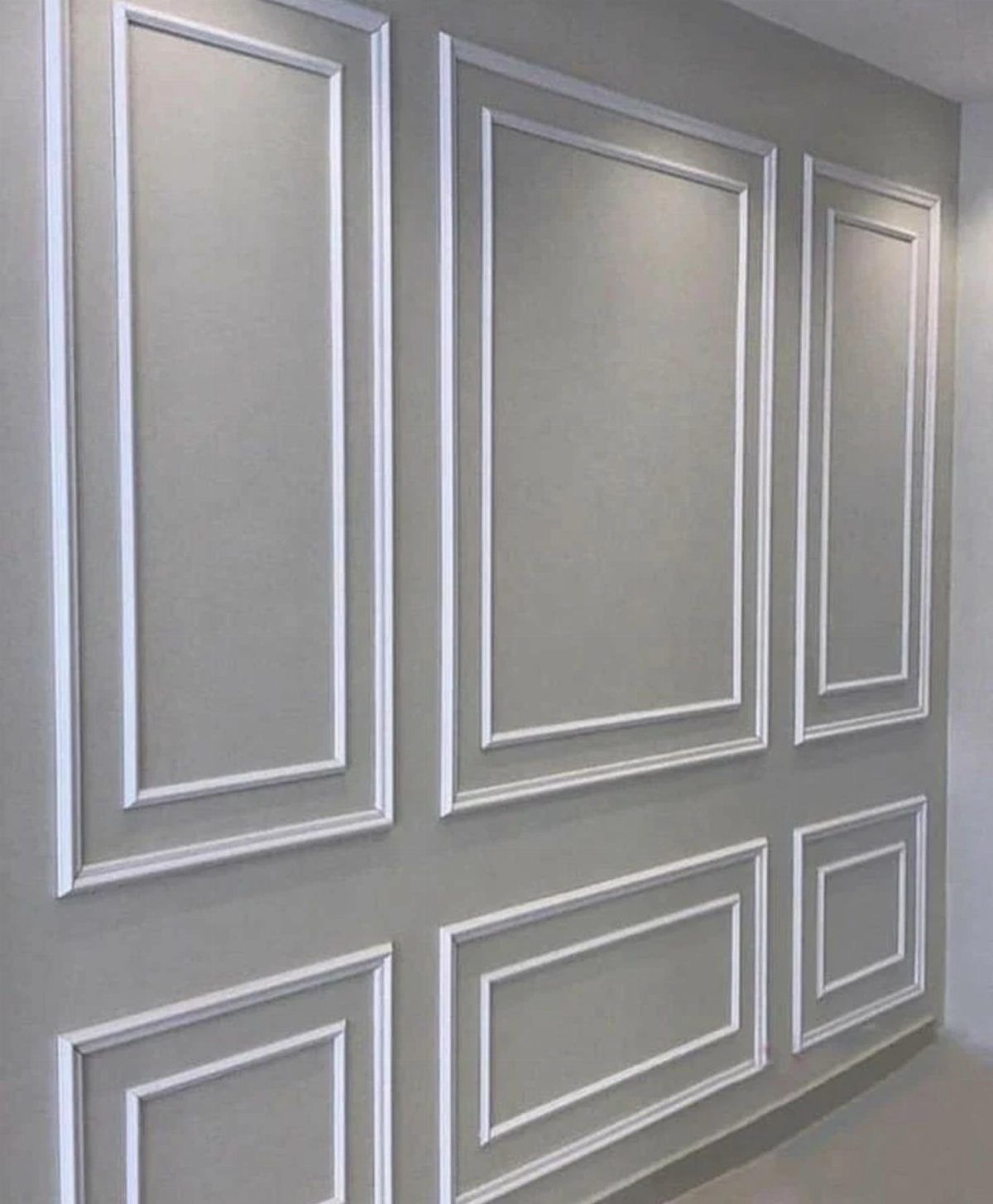 White decorative molding frames on a grey wall creating elegant French wall paneling.