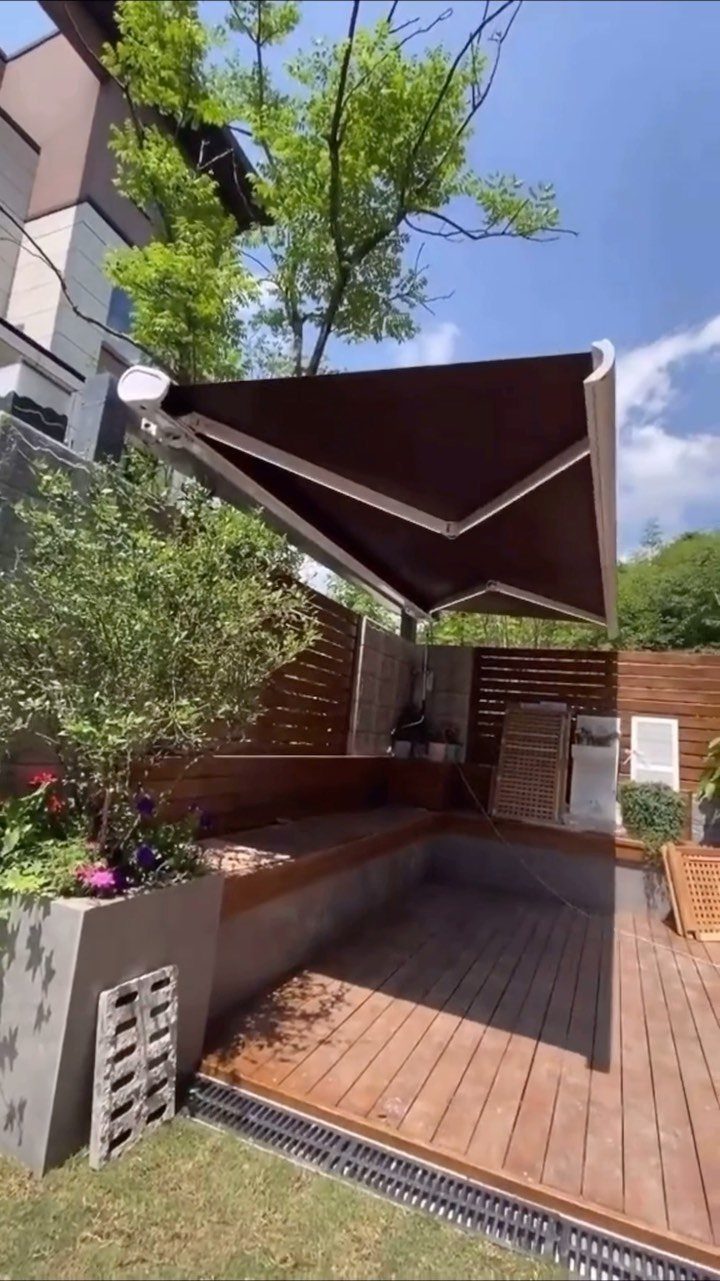 20 Garden Ideas for Small Spaces, From Vertical to Fire Pits 17 Brown retractable canopy providing shade over a wooden deck patio with built-in seating.