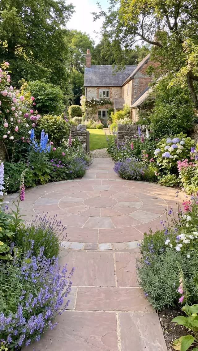20 Garden Ideas for Small Spaces, From Vertical to Fire Pits 12 Stone pathway and circular patio surrounded by colorful flowers leading to a cottage.