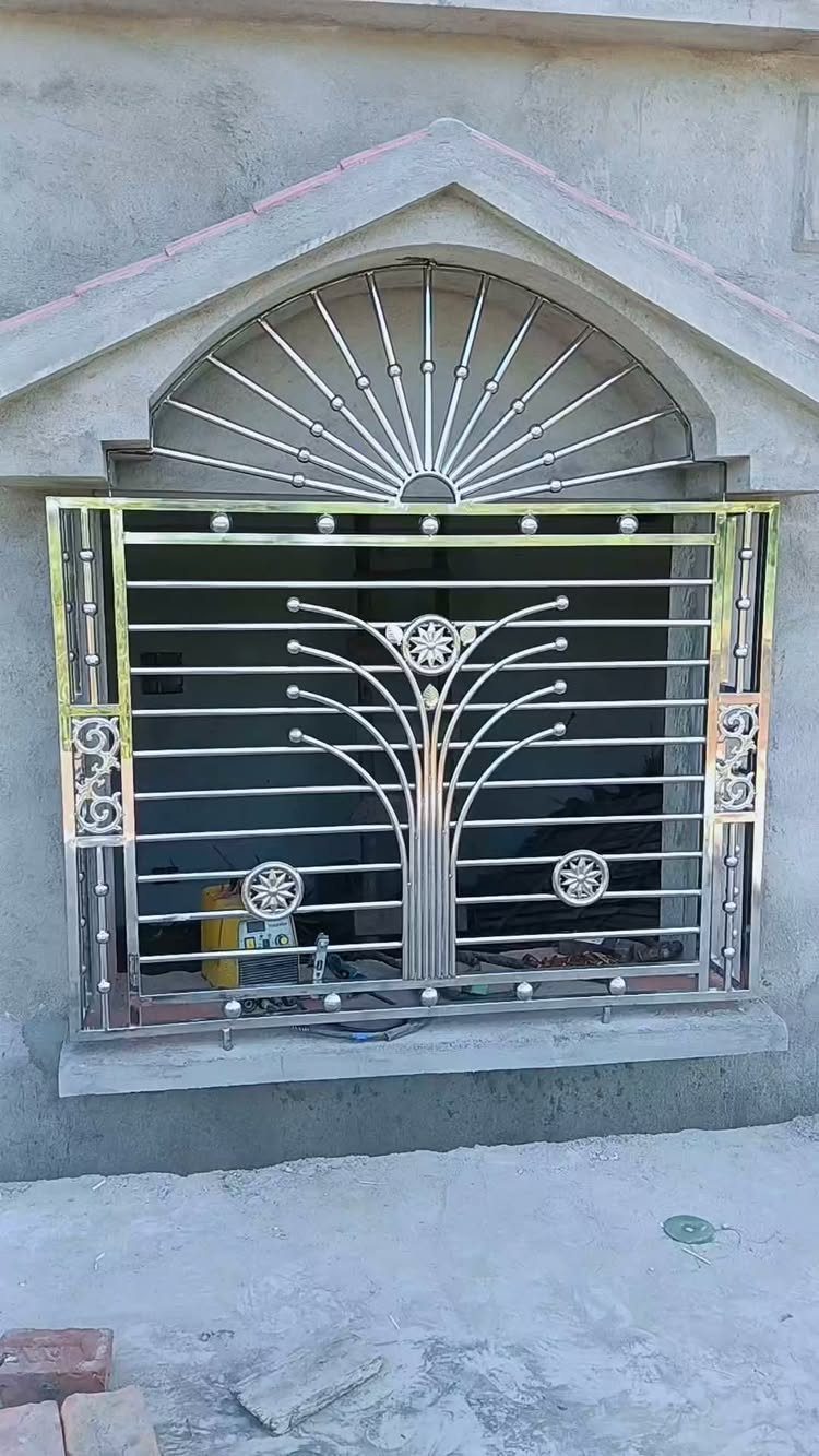 Stainless steel window grill with horizontal bars and a decorative sunburst top arch.