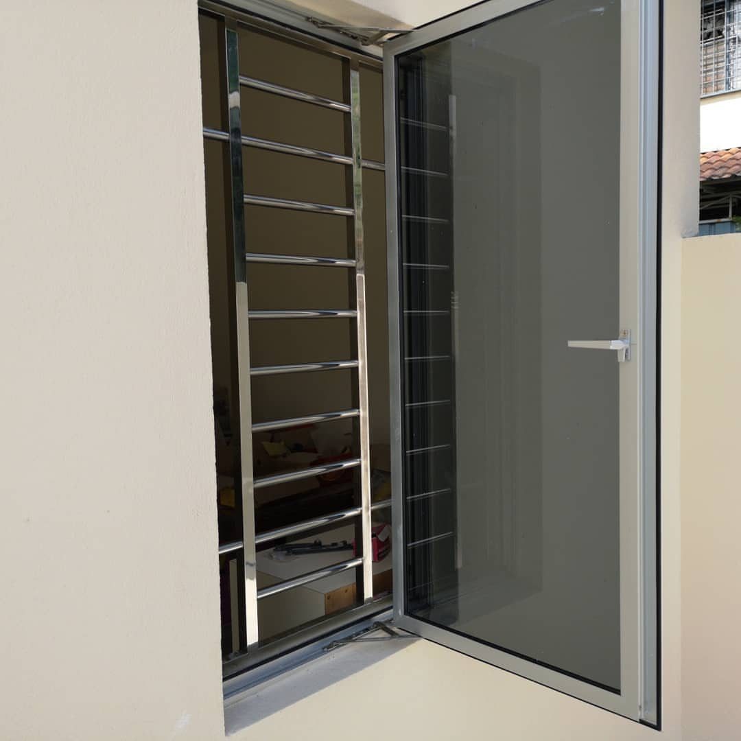 Silver metal security grill on a window with an open glass pane.