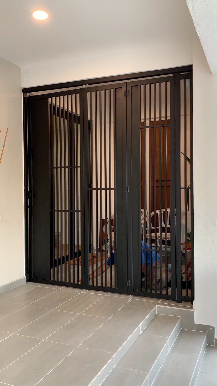 Black metal security grill with vertical bars installed at a home entrance.