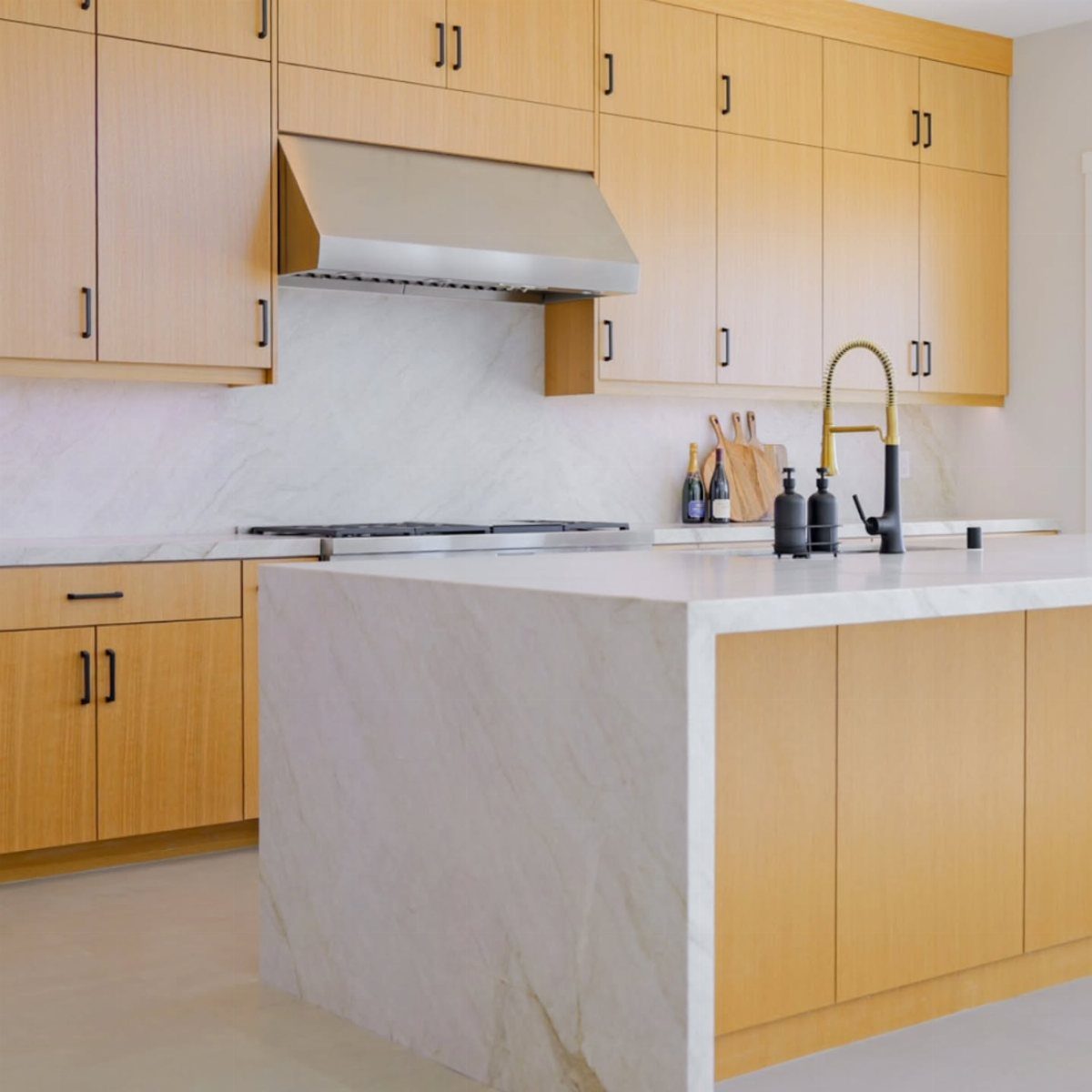 Honey Oak Wood Floors: 8 Design Ideas That Work 3 Light wood kitchen cabinets featuring black hardware and white marble countertops and island.
