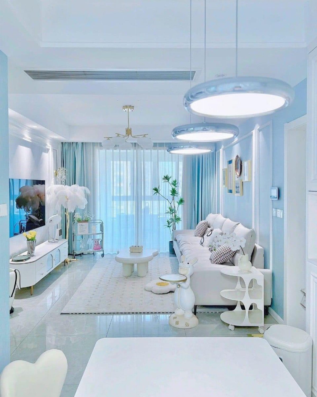 Interior Color Schemes: 9 Real Rooms That Make Them Work 4 A bright modern living room decorated with light blue walls, white furniture, and blue curtains.