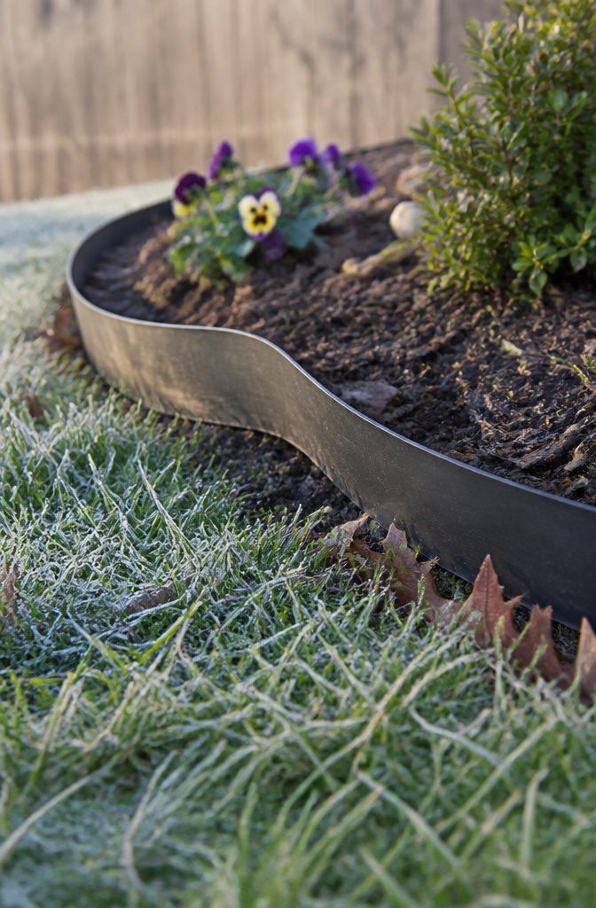 Landscape Bed Edging: Materials, Styles and How They Hold Up 4 Black plastic edging curving along a garden bed beside grass