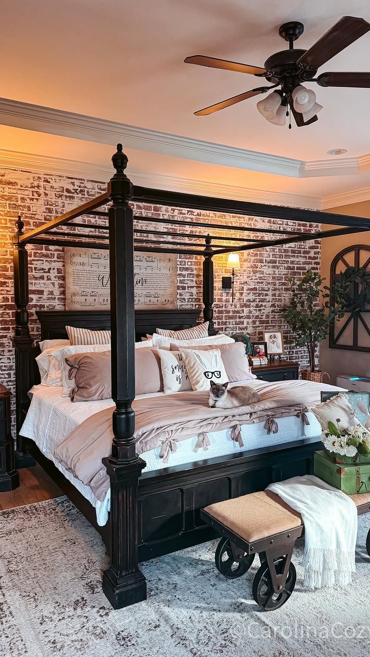 A dark wood canopy bed with white bedding set against a brick-patterned accent wall.