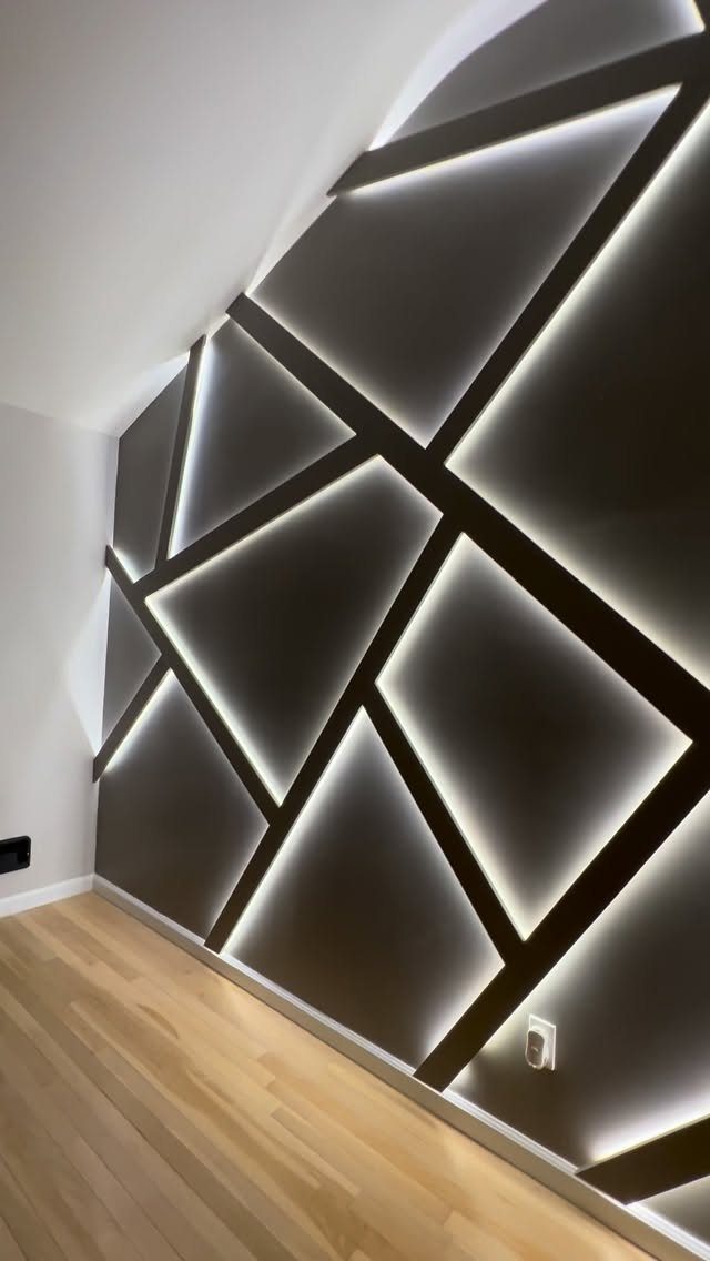 Geometric dark wall panels with glowing white LED light strips integrated into the intersecting lines.