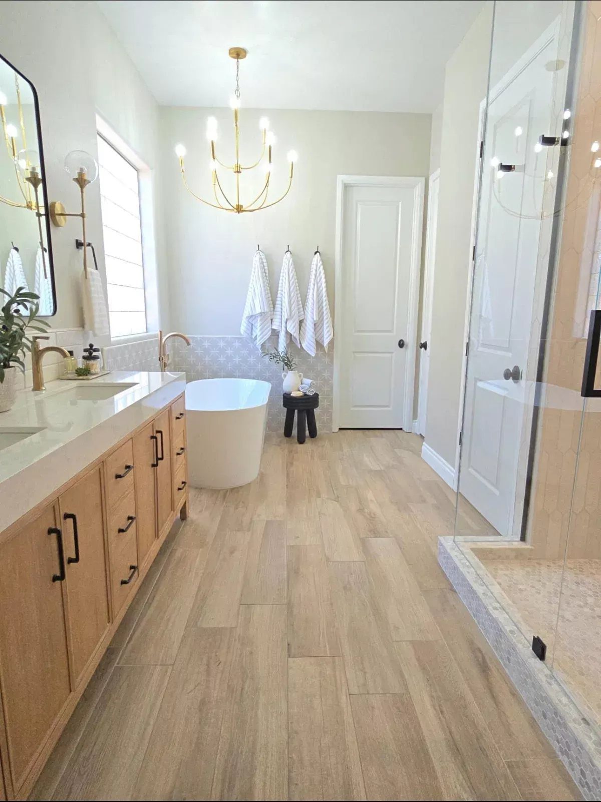 Light LVP Flooring: 5 Design Ideas for Bright Rooms 3 Light wood-look plank flooring in a bright, modern bathroom with a white bathtub and vanity.