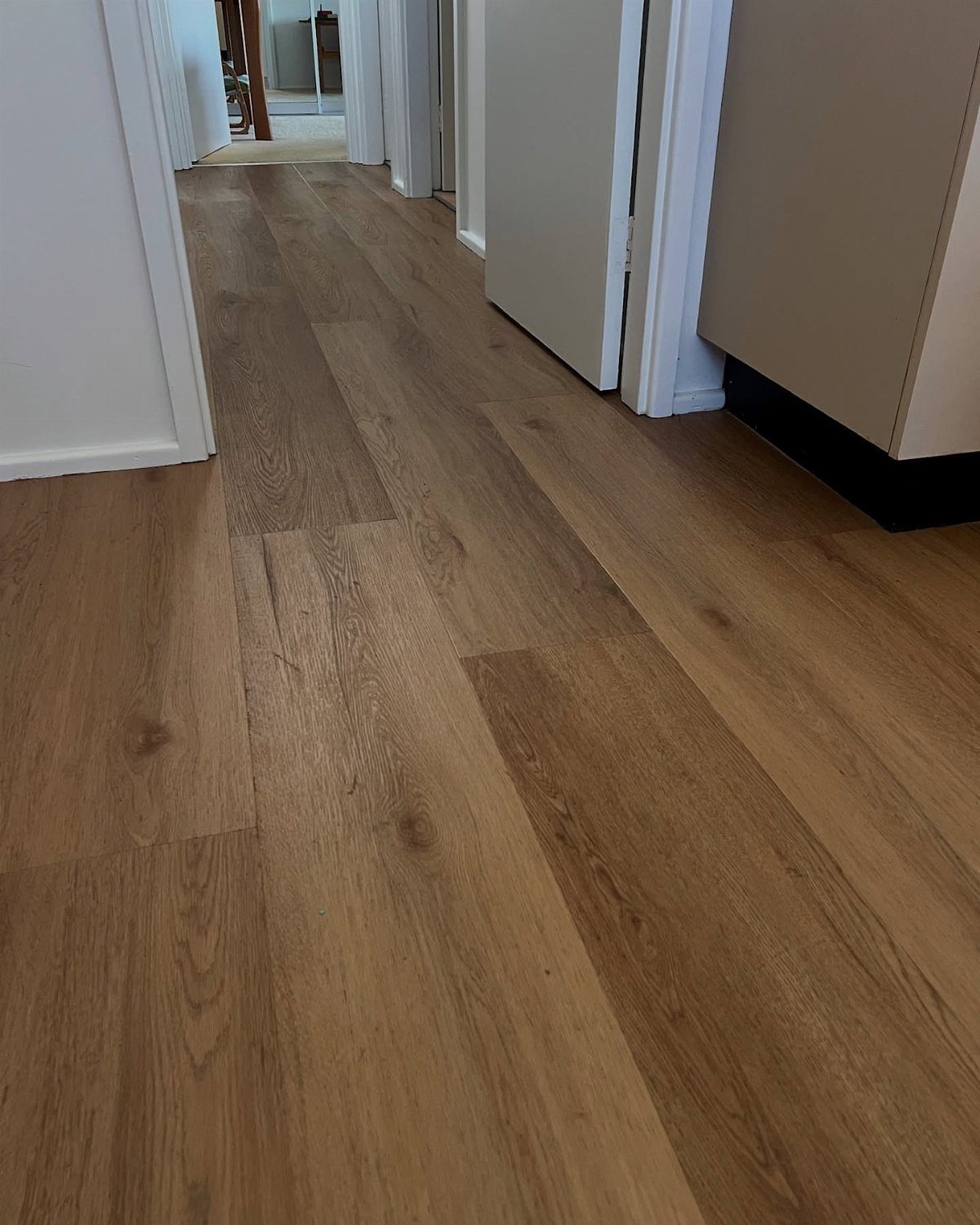 Light LVP Flooring: 5 Design Ideas for Bright Rooms 2 Light brown wood-look vinyl plank flooring with visible grain patterns installed in a hallway.