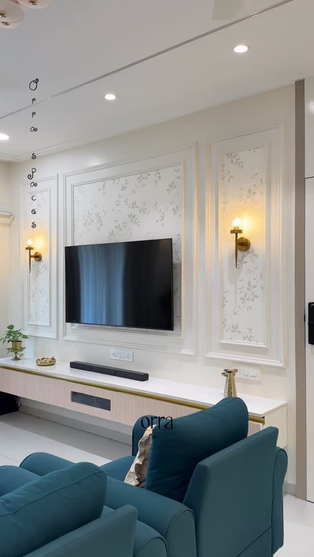 White decorative wall molding panels with floral wallpaper and gold sconces in a living room.
