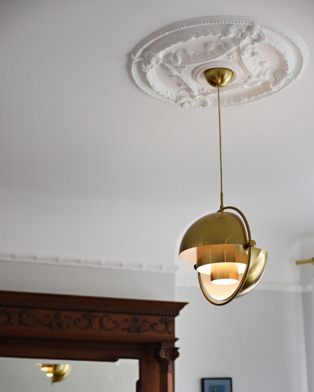 Ornate white circular ceiling medallion with a gold modern pendant light hanging down.