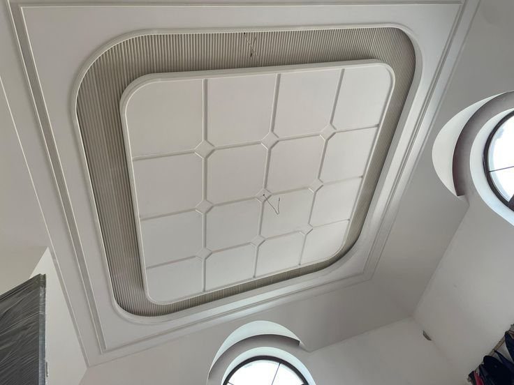 Multilevel white POP ceiling with a central grid and layered rectangular framing.