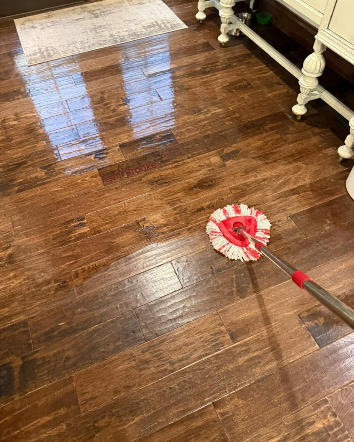 LVP That Looks Like Real Wood: 6 Ideas to Pull It Off 2 A red and white string mop cleaning a dark wood-look luxury vinyl plank floor.