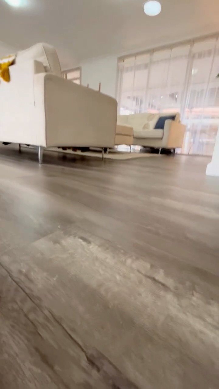 LVP That Looks Like Real Wood: 6 Ideas to Pull It Off 5 Grey wood-look flooring planks in a bright living room with a white sofa.